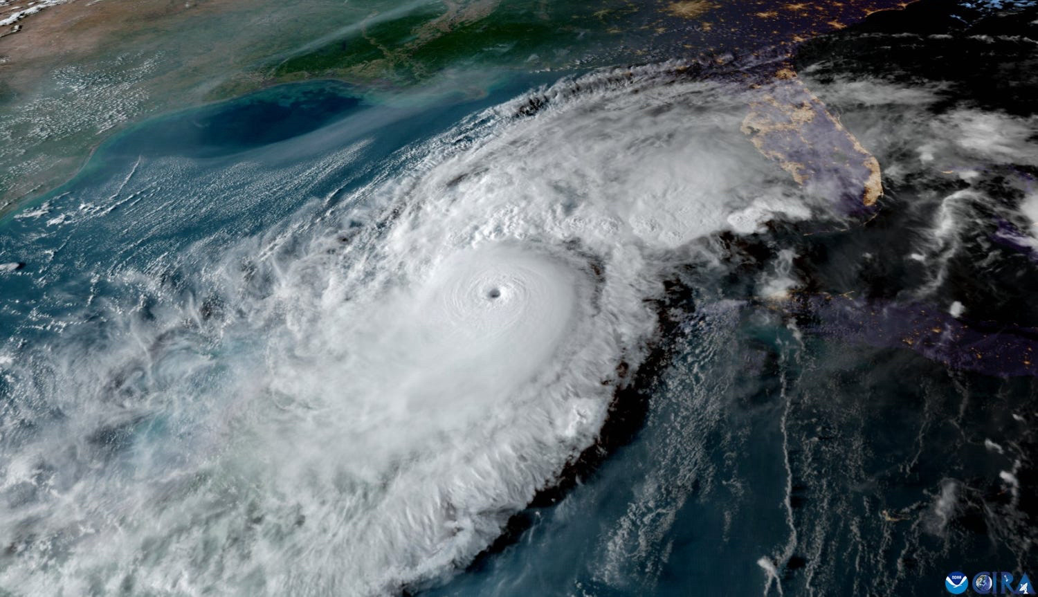 Photograph of gigantic Hurricane Milton bearing down on Florida, the penninsula’s shape framed by the bright lights of its coastal conurbations, with interior cities like Orlando clearly marked.