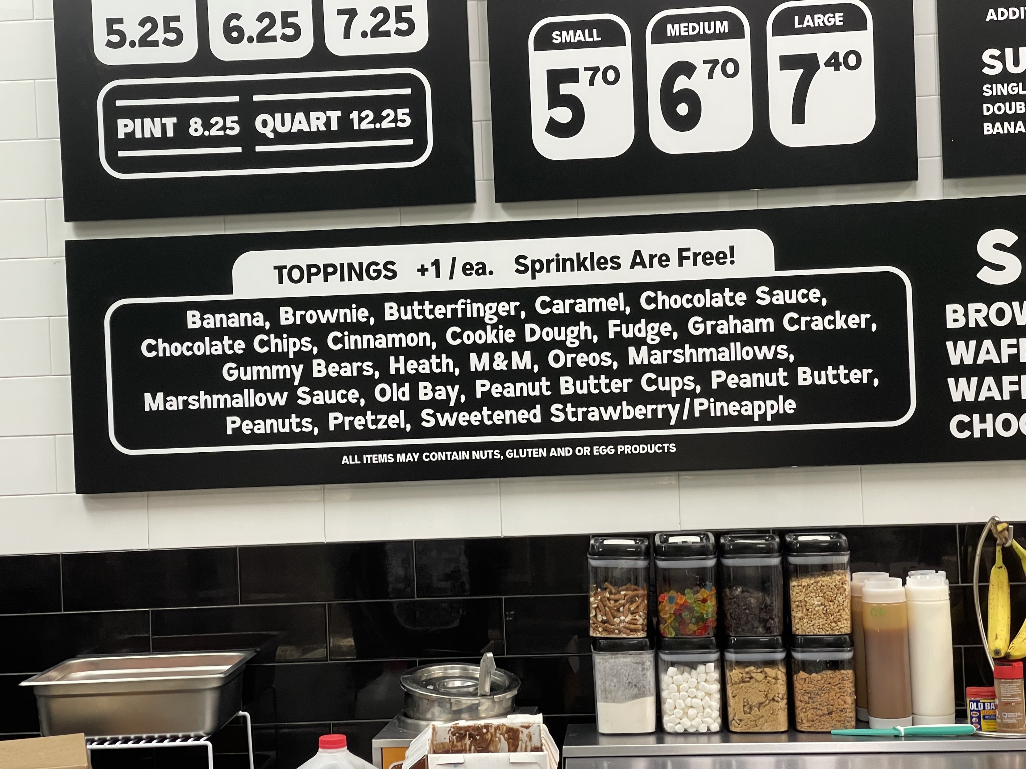 Photo of toppings available on an ice cream shop menu: Banana, Brownie, Butterfinger, Caramel, Chocolate Sauce, Chocolate Chips, Cinnamon, Cookie Dough, Fudge, Graham Cracker, Gummy Bears, Heath, M&M, Oreos, Marshmallows,
Marshmallow Sauce, Old Bay, Peanut Butter Cups, Peanut Butter, Peanuts, Pretzel, Sweetened Strawberry/Pineapple